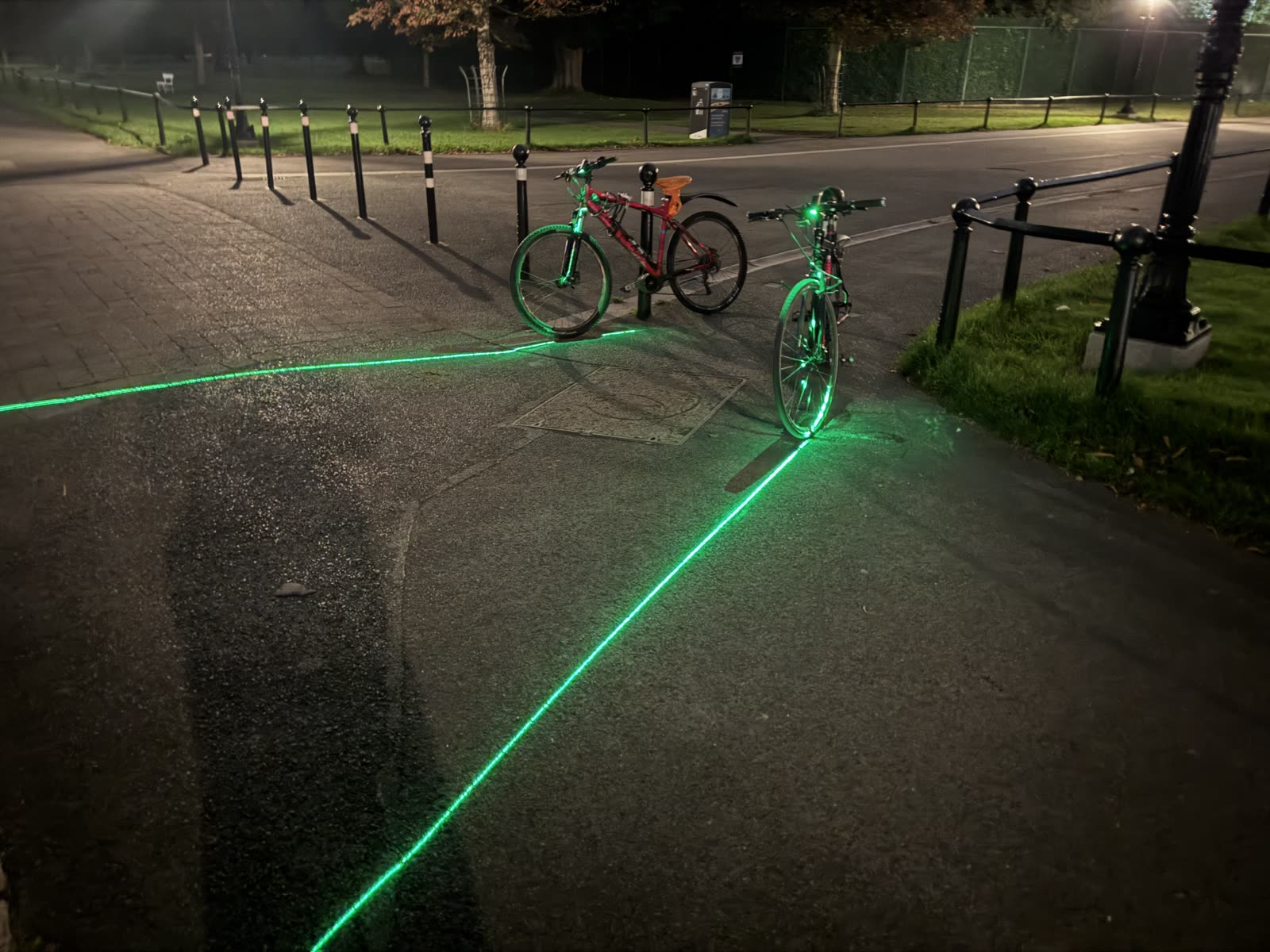 A bike at night with a bright green laser lane projected along the road surface